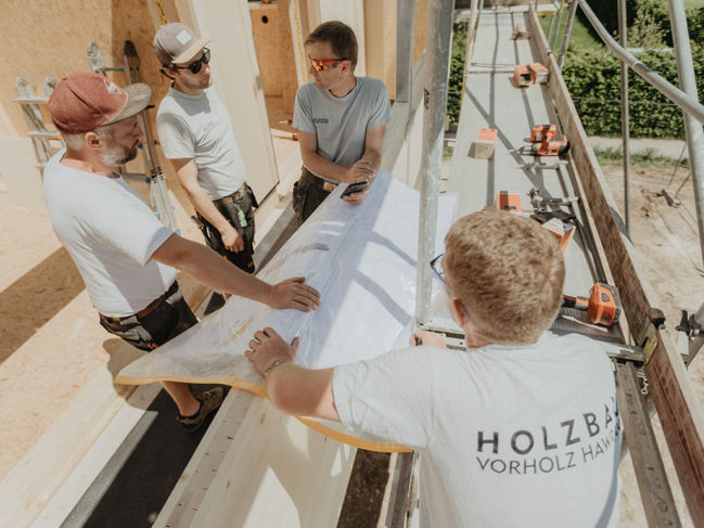 Zimmerer besprechen Bauplan auf Baustelle in Holzbauweise